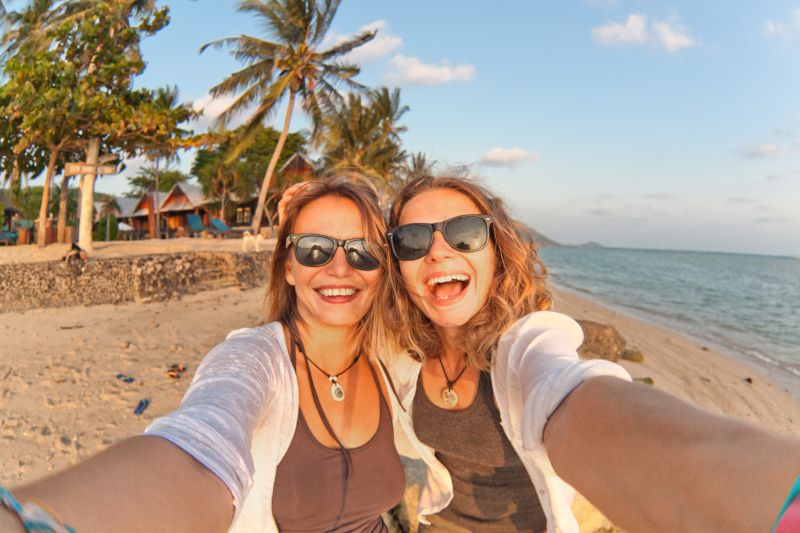 Two happy girlfriends making selfie on the coast of tropical sea