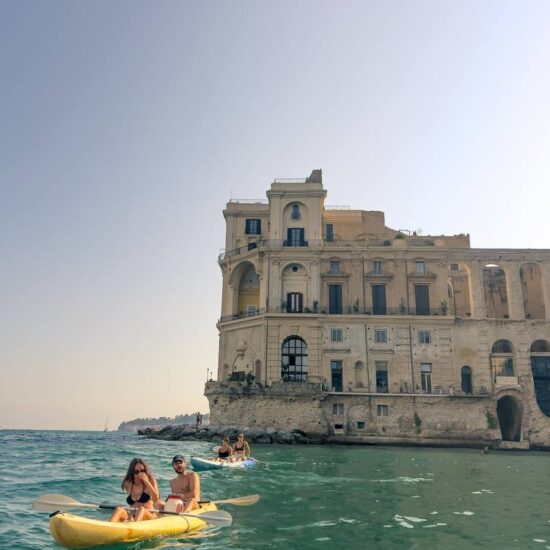 excursionist in kayak paddling infront Palazzo Donn'anna a Napoli