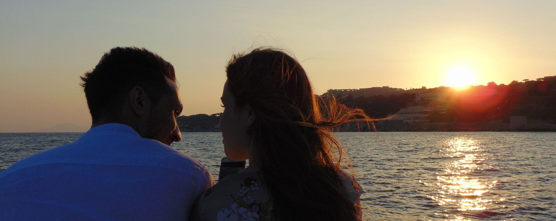 Giovane coppia si gode il tramonto in barca nel Golfo di Napoli