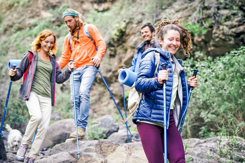 Group of friends with backpacks doing trekking excursion on mountain - Young tourists walking and exploring the nature - Trekker, hike and travel people concept