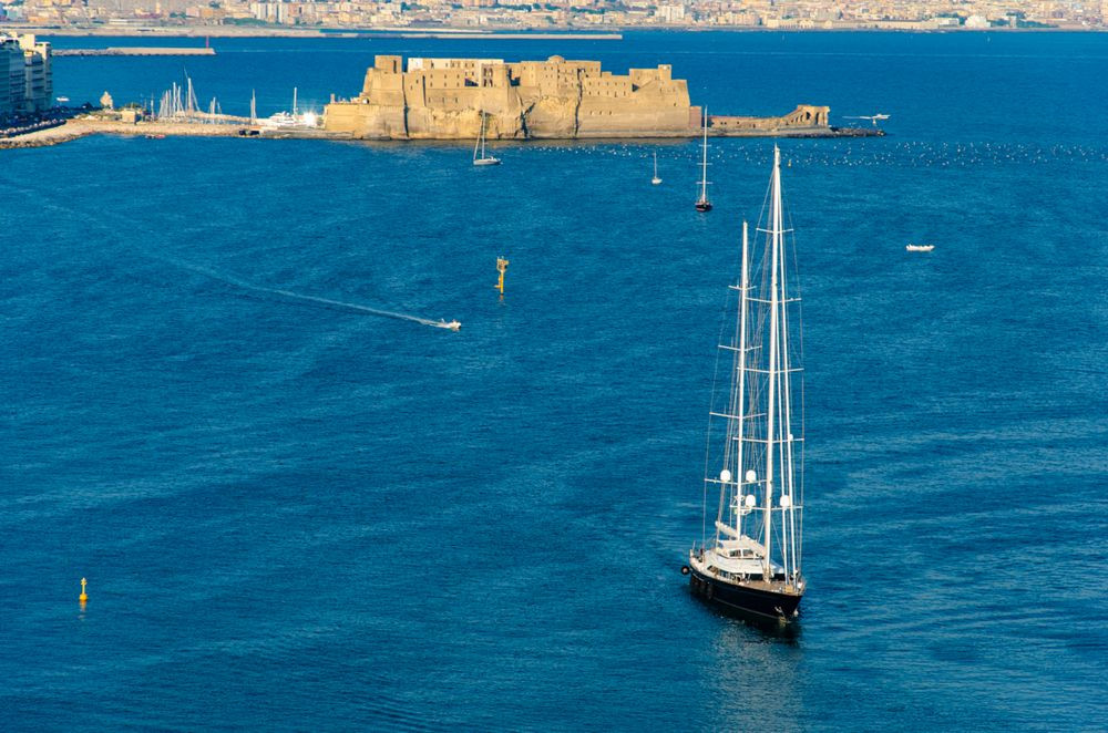 Sailboat at Tyrrhenian sea and Egg castle on background in Naples, Italy. Aerial view, card design.