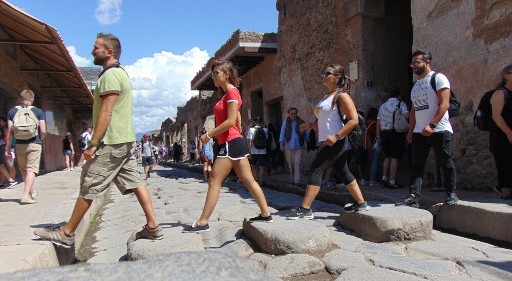 Four young people walk in pompeii like the Beatles in Abbey Road