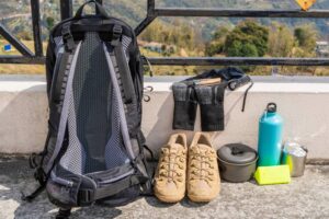 Trecking or hiking equipment - bagpack, boots, socks, folding knife, gas burner, water flask, kettle pot and flashlight. Outdoor activity concept. Still life close up stock photo.