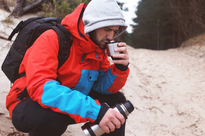 Escursionista in sosta che beve dalla borraccia durante il trekking