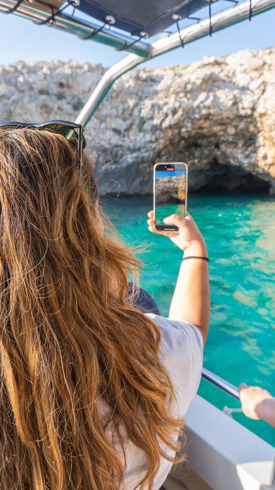 ragazza fotografa una delle baie che si visitano in barca a Santa Maria di Leuca