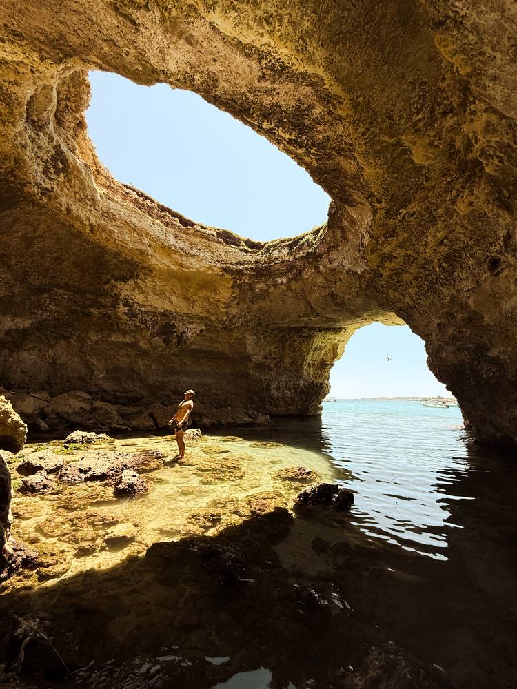 ragazzo all'interno della grotta a cupola aperta della Baia del Mulino d'Acqua